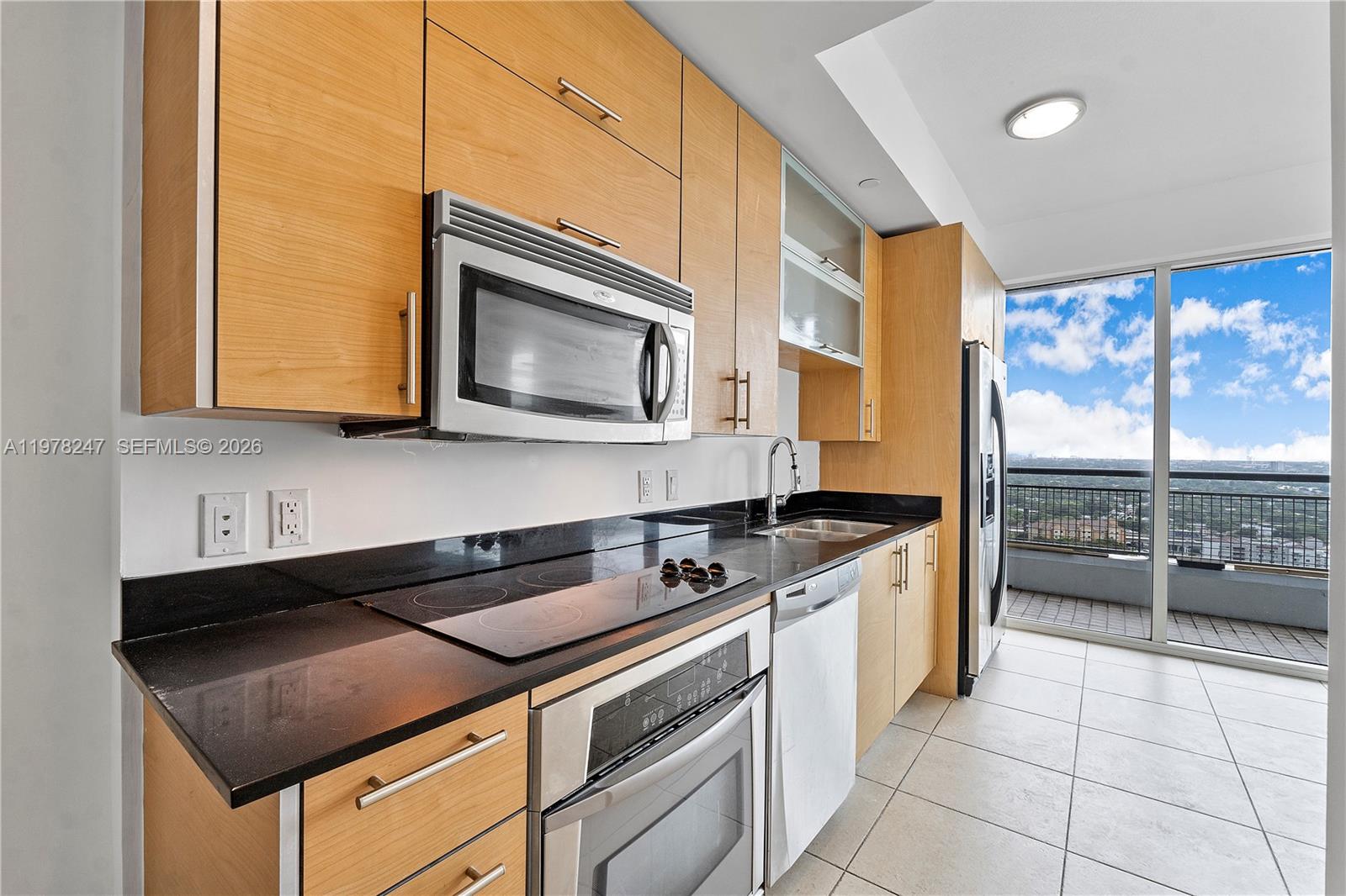 60 Southwest 13th Street, Unit 1921 Miami, FL 33130 - Photo 5 of 23 a kitchen with stainless steel appliances granite countertop a stove a sink and a microwave