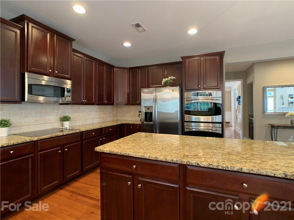1920 Faison Avenue Fort Mill, SC 29708 - Photo 22 of 47 a kitchen with kitchen island granite countertop wooden cabinets a refrigerator and a sink