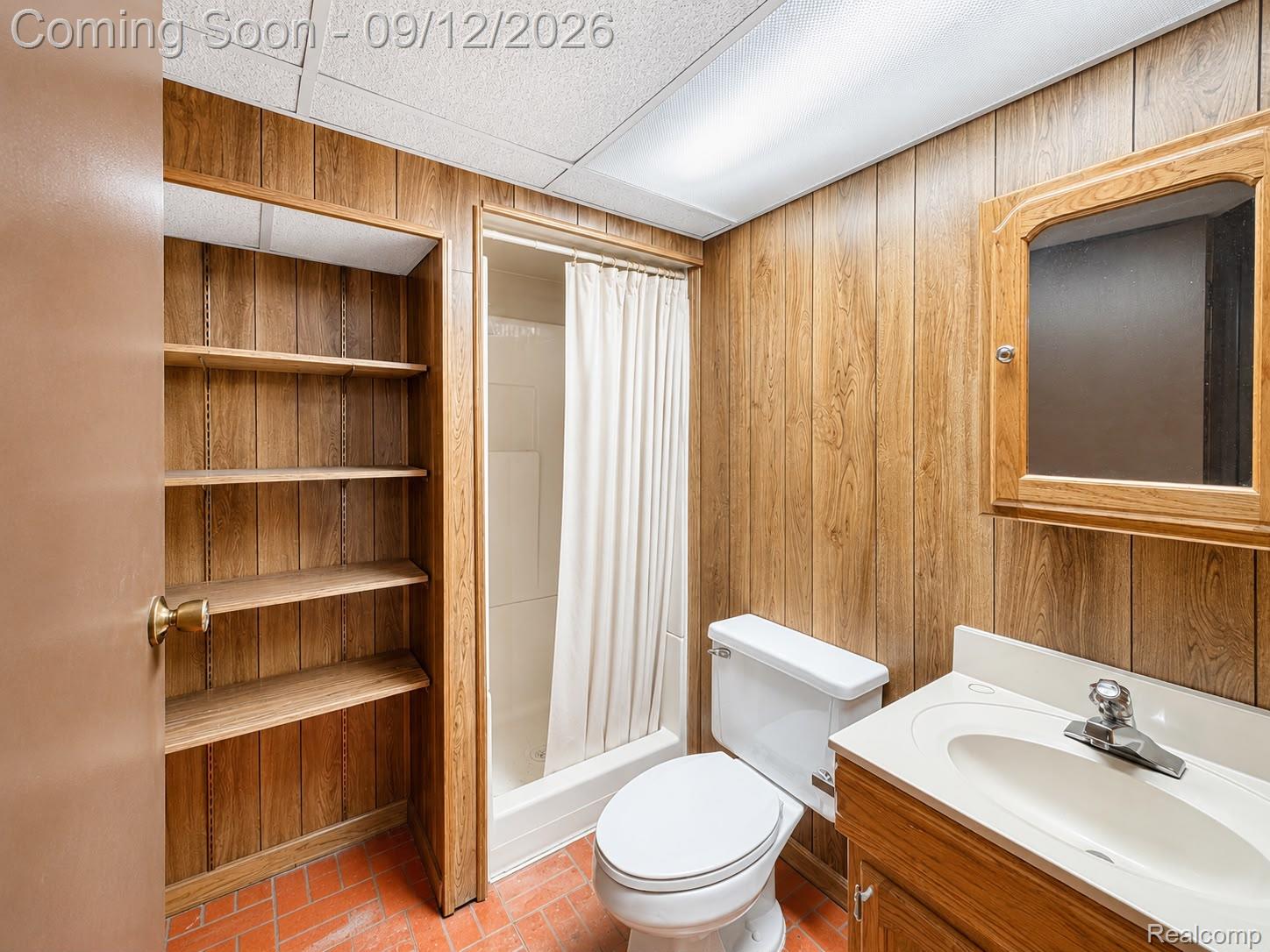 34398 Greentrees Road Sterling Heights, MI 48312 - Photo 25 of 36 Bathroom featuring wood-finish paneling, an integrated sink vanity, a medicine cabinet, a shower stall, and built-in shelving