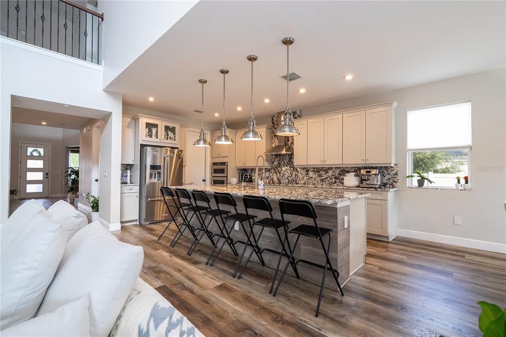16894 Wingspread Loop Winter Garden, FL 34787 - Photo 23 of 53 a kitchen with stainless steel appliances kitchen island granite countertop a stove a sink a refrigerator and white cabinets with wooden floor