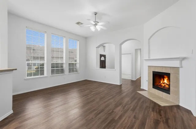 a view of an empty room with wooden floor fireplace and a window