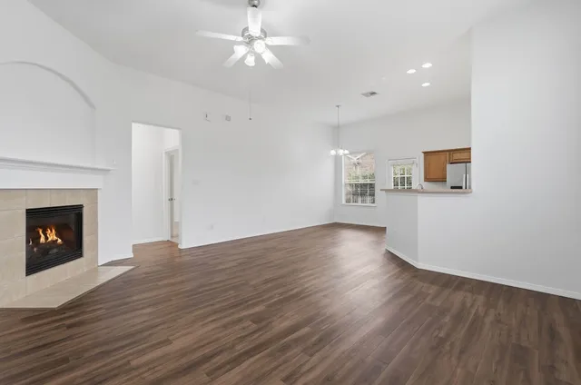 a view of an empty room with wooden floor fireplace and a window