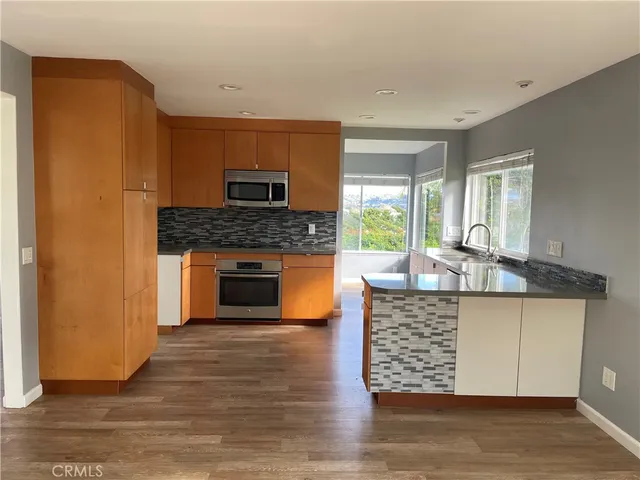 a kitchen with granite countertop a stove top oven a sink and a wooden floor