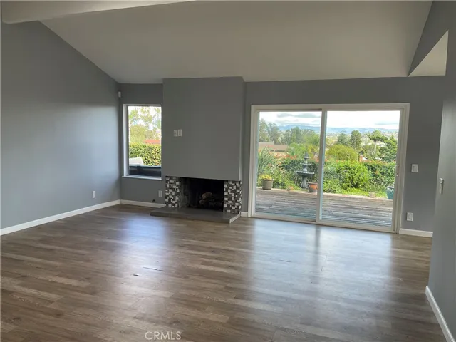 a view of empty room with wooden floor and fireplace