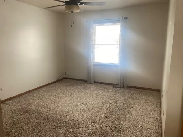 an empty room with a ceiling fan and window