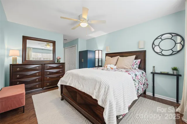 a bedroom with a bed and dresser with wooden floor