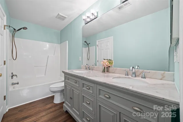 a bathroom with a granite countertop sink toilet a large mirror a bathtub and shower