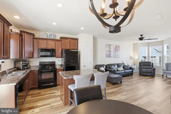 a kitchen with stainless steel appliances granite countertop a stove top oven a refrigerator a sink and dining table with chairs