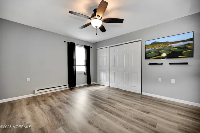 a view of an empty room with window and wooden floor