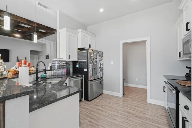 a kitchen with stainless steel appliances granite countertop a refrigerator a stove and a sink