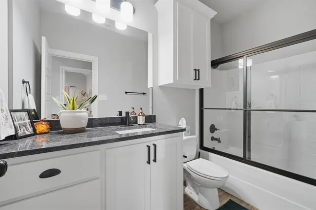 a bathroom with a granite countertop sink a toilet a mirror and shower