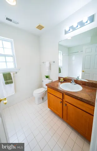 a spacious bathroom with a granite countertop sink a toilet a mirror and shower