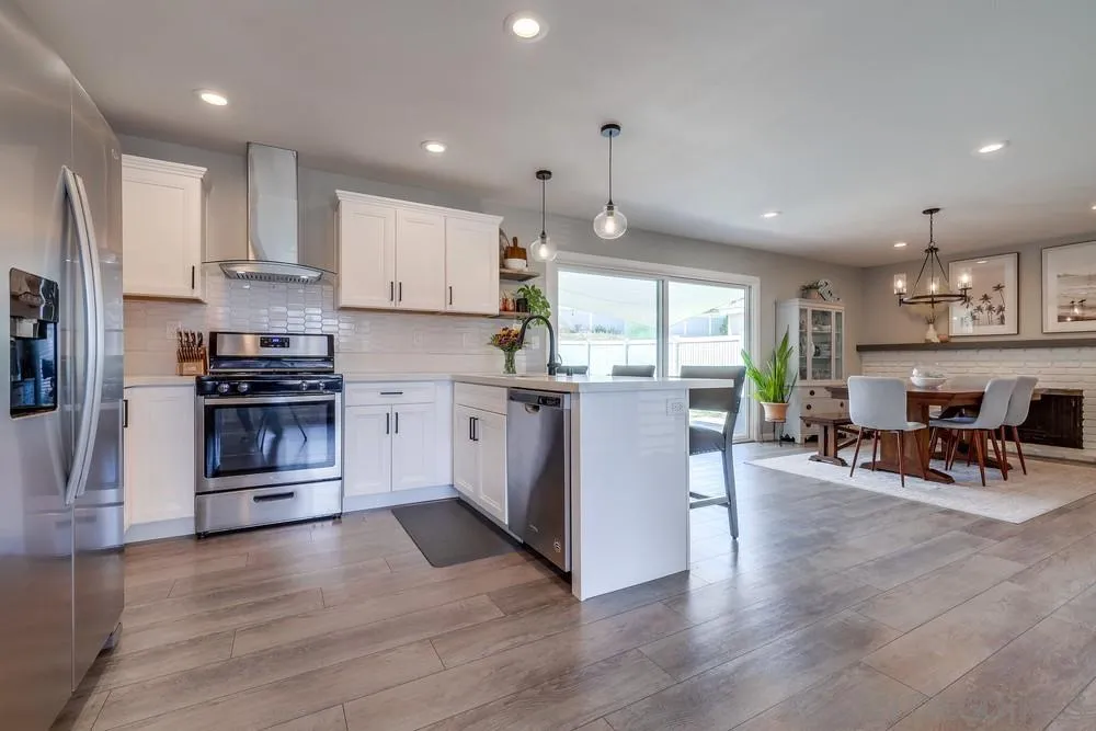 10262 Molino Road Santee, CA 92071 - Photo 3 of 26 a kitchen with stainless steel appliances kitchen island granite countertop a stove top oven a sink a dining table and chairs with wooden floor
