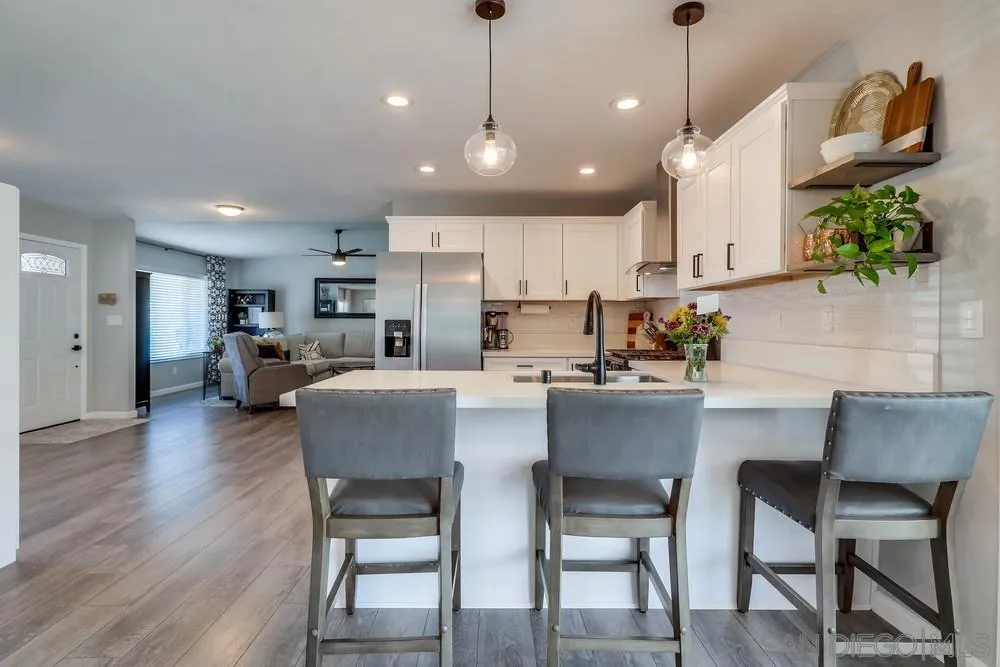 10262 Molino Road Santee, CA 92071 - Photo 6 of 26 a kitchen with stainless steel appliances granite countertop a table chairs refrigerator and microwave