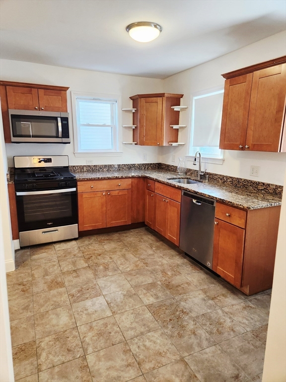 321 East Street Dedham, MA 02026 - Photo 6 of 18 a large kitchen with granite countertop a stove top oven microwave and cabinets
