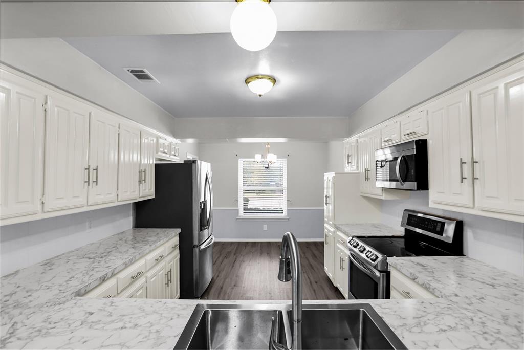 1327 Big Stone Gap Road Duncanville, TX 75137 - Photo 20 of 36 a kitchen with stainless steel appliances granite countertop a sink a stove top oven a counter space and cabinets