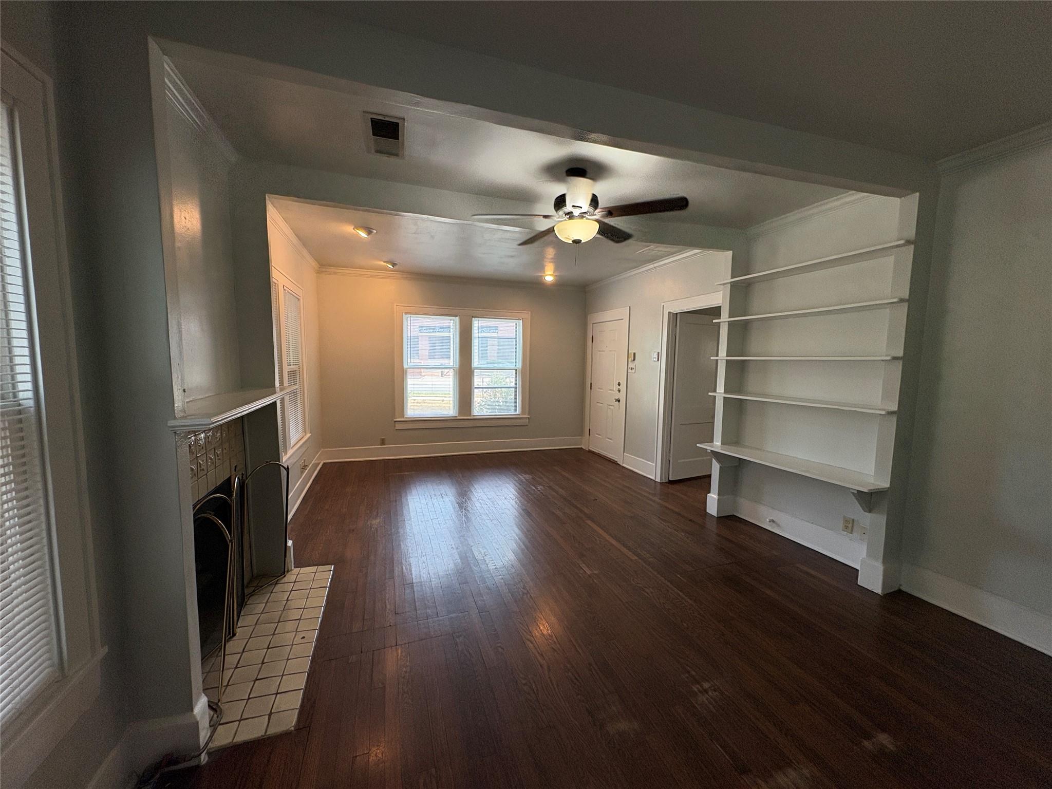 915 West 29th Street Austin, TX 78705 - Photo 3 of 20 Spacious room featuring wood-finish flooring, a decorative fireplace with tile surround, an overhead ceiling fan, recessed lighting, and built-in shelving