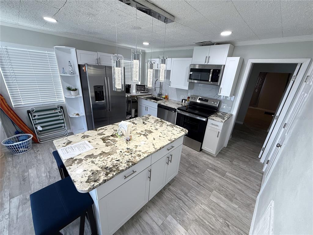 13711 Gulf Boulevard, Unit 1 Madeira Beach, FL 33708 - Photo 11 of 36 a kitchen with stainless steel appliances kitchen island granite countertop a refrigerator stove and microwave