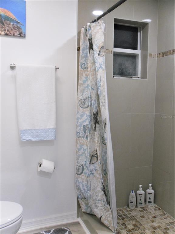 13711 Gulf Boulevard, Unit 1 Madeira Beach, FL 33708 - Photo 20 of 36 a bathroom with a granite countertop shower a toilet and a shower
