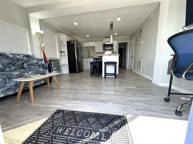 a kitchen with stainless steel appliances kitchen island granite countertop a refrigerator a sink a stove top oven and wooden floor