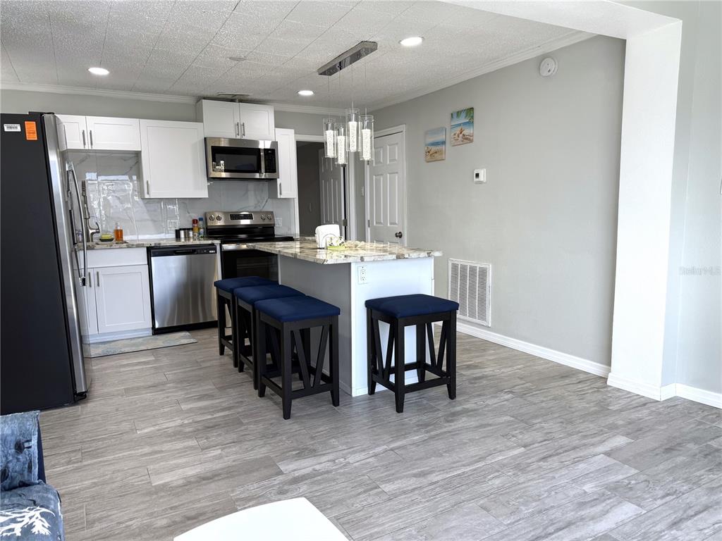 13711 Gulf Boulevard, Unit 1 Madeira Beach, FL 33708 - Photo 27 of 36 a kitchen with kitchen island granite countertop stainless steel appliances a dining table and chairs