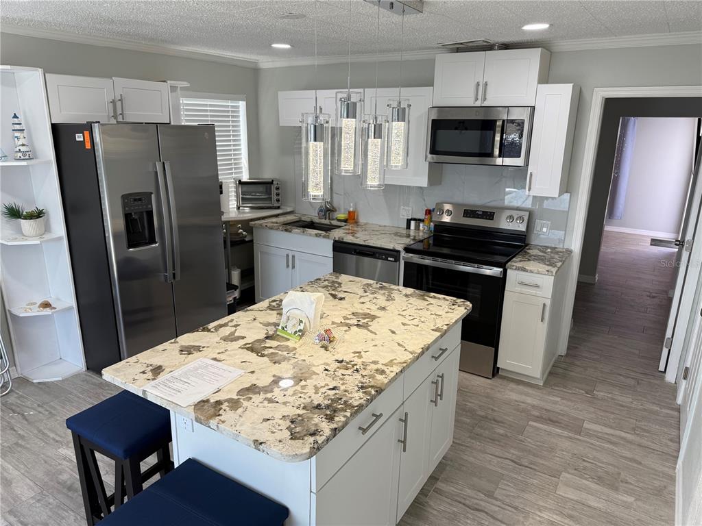 13711 Gulf Boulevard, Unit 1 Madeira Beach, FL 33708 - Photo 29 of 36 a kitchen with stainless steel appliances kitchen island granite countertop a refrigerator stove microwave and sink
