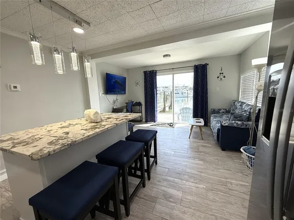 a kitchen with stainless steel appliances granite countertop a stove a refrigerator a sink a dining table and chairs with wooden floor