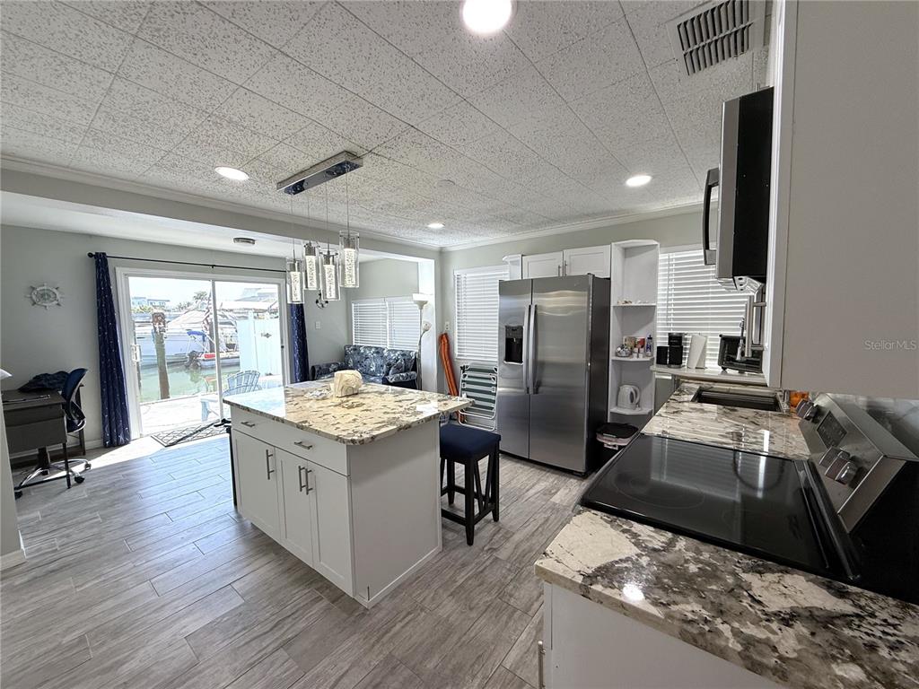 13711 Gulf Boulevard, Unit 1 Madeira Beach, FL 33708 - Photo 8 of 36 a kitchen with stainless steel appliances granite countertop a sink stove and refrigerator