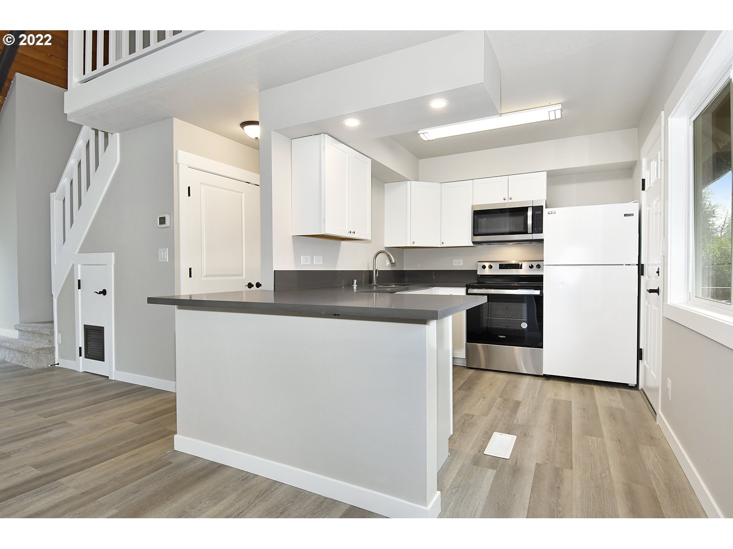23706 Northeast 10th Avenue Ridgefield, WA 98642 - Photo 11 of 32 a kitchen with stainless steel appliances granite countertop a refrigerator a stove a sink and white cabinets with wooden floor