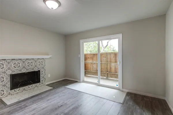 a view of an empty room with wooden floor and a fireplace