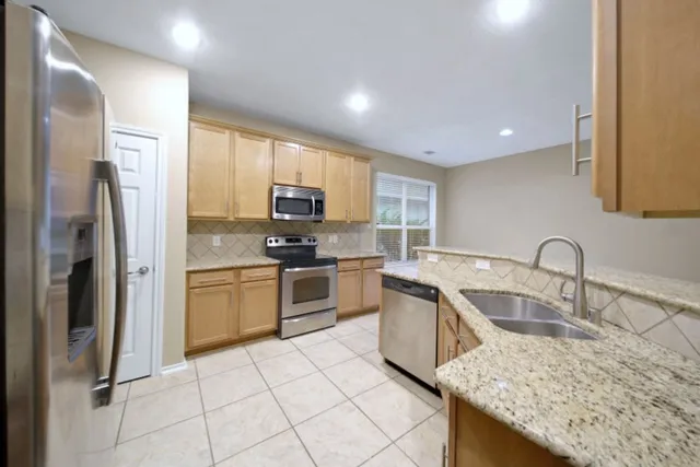 a kitchen with granite countertop a sink stainless steel appliances and cabinets