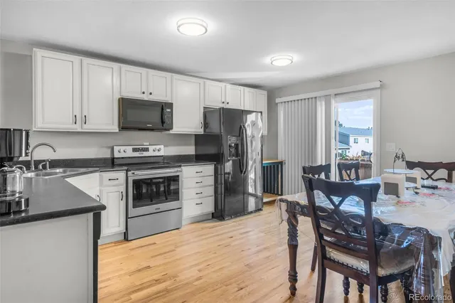 a kitchen with stainless steel appliances a stove a sink dishwasher a refrigerator with a dining table and chairs