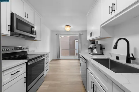 a kitchen with stainless steel appliances a stove top oven a sink and a window