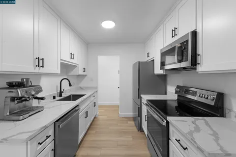 a kitchen with stainless steel appliances a sink and wooden floor