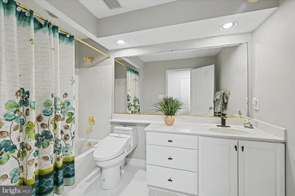 a bathroom with a granite countertop sink a toilet a mirror and shower