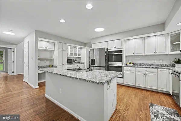a kitchen with stainless steel appliances granite countertop a stove a sink and white cabinets