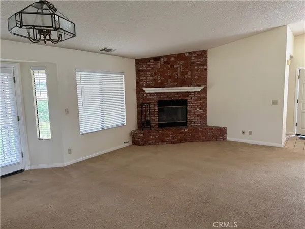 an empty room with windows fireplace and fan