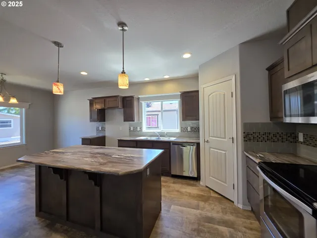 a kitchen with stainless steel appliances granite countertop a sink refrigerator and microwave