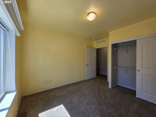 an empty room with closet and windows