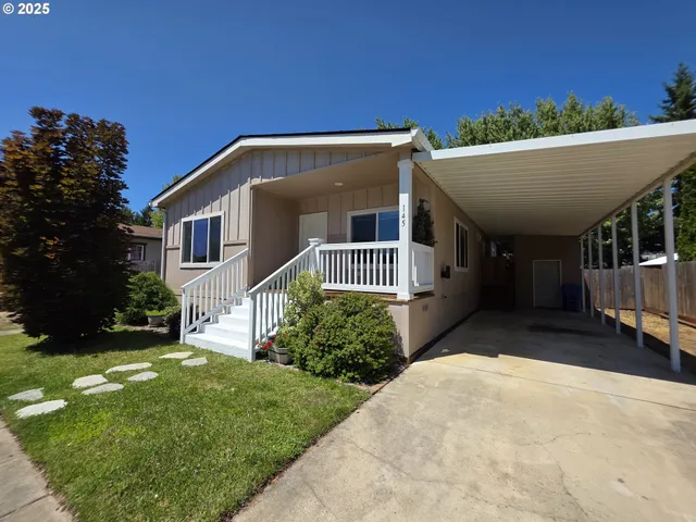 a view of a house with a small yard and a large tree