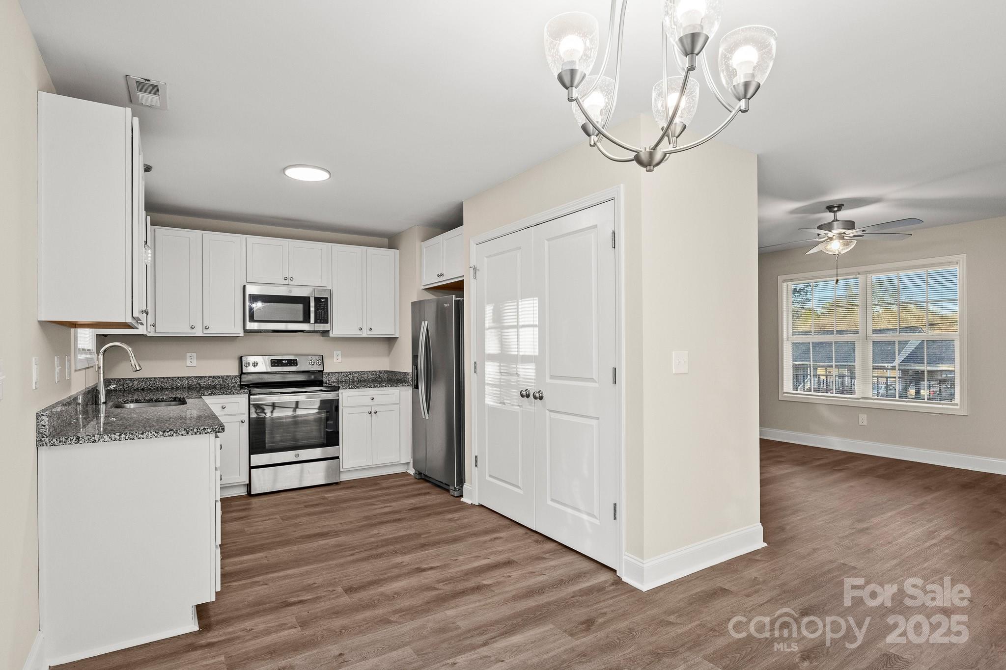1219 Calhoun Street Rock Hill, SC 29732 - Photo 8 of 33 a kitchen with stainless steel appliances granite countertop a refrigerator a stove a sink and white cabinets with wooden floor