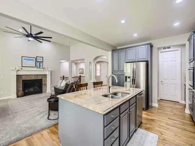 a view of kitchen island a sink wooden floor and a fireplace