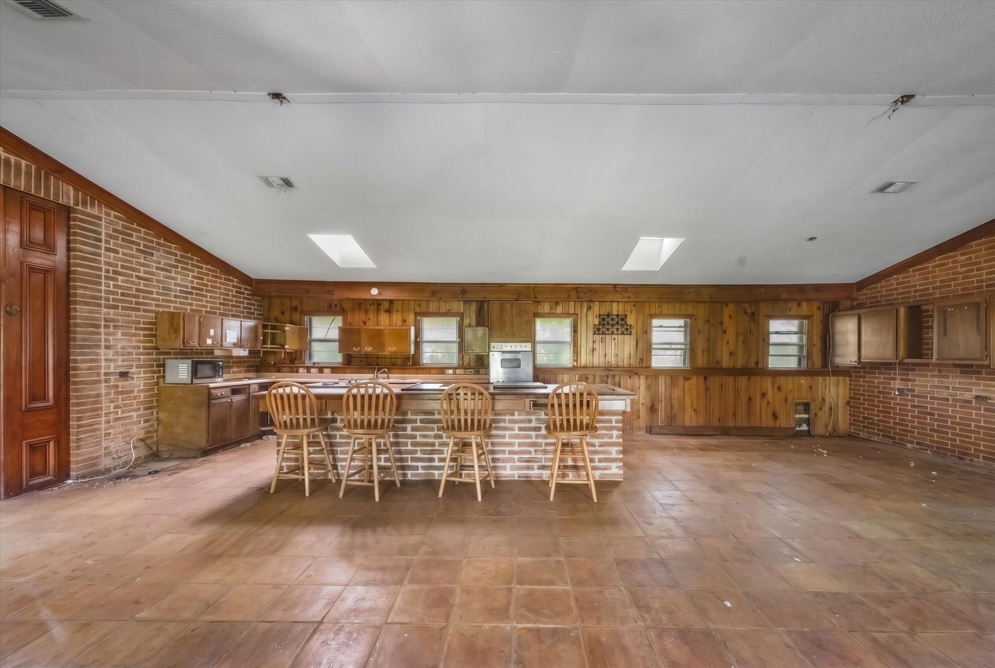 14201 Lund - Carlson Road Coupland, TX 78615 - Photo 35 of 40 A spacious kitchen with a brick island, warm wood paneling, and skylights for natural illumination.