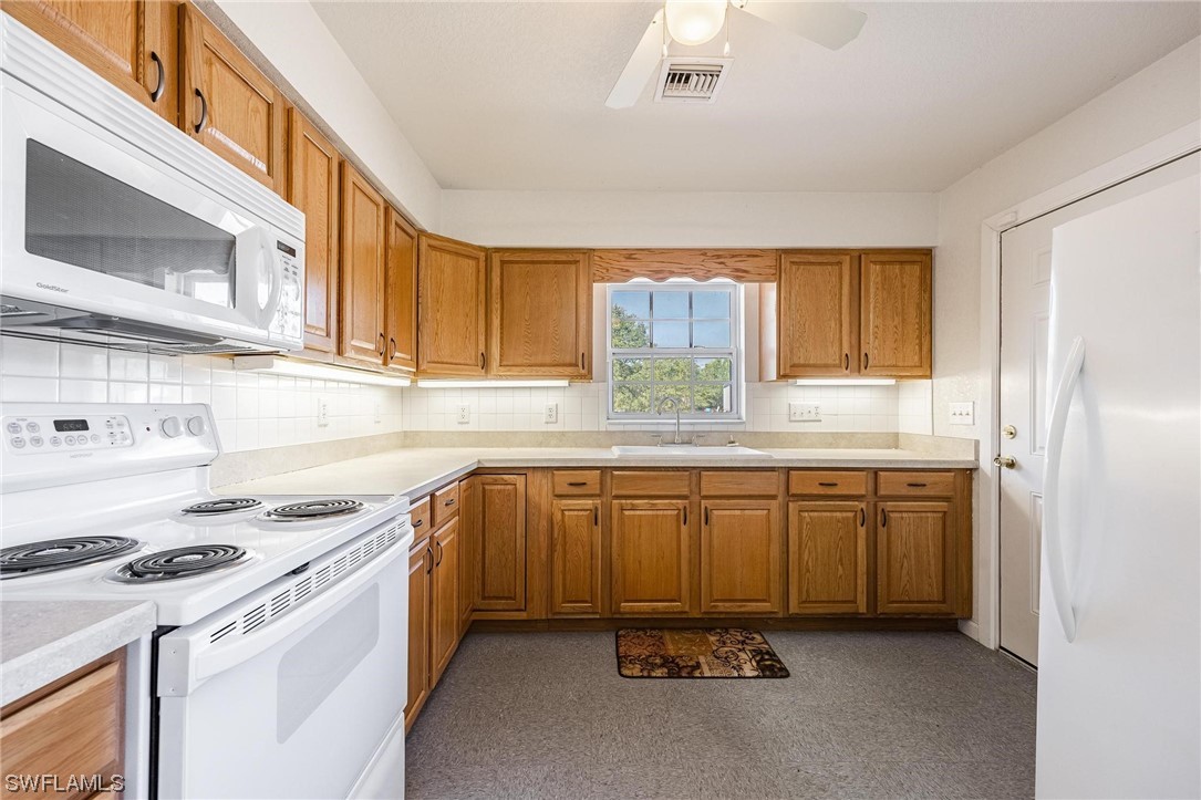 7764 14th Place LaBelle, FL 33935 - Photo 26 of 34 a kitchen with granite countertop a sink stove and refrigerator