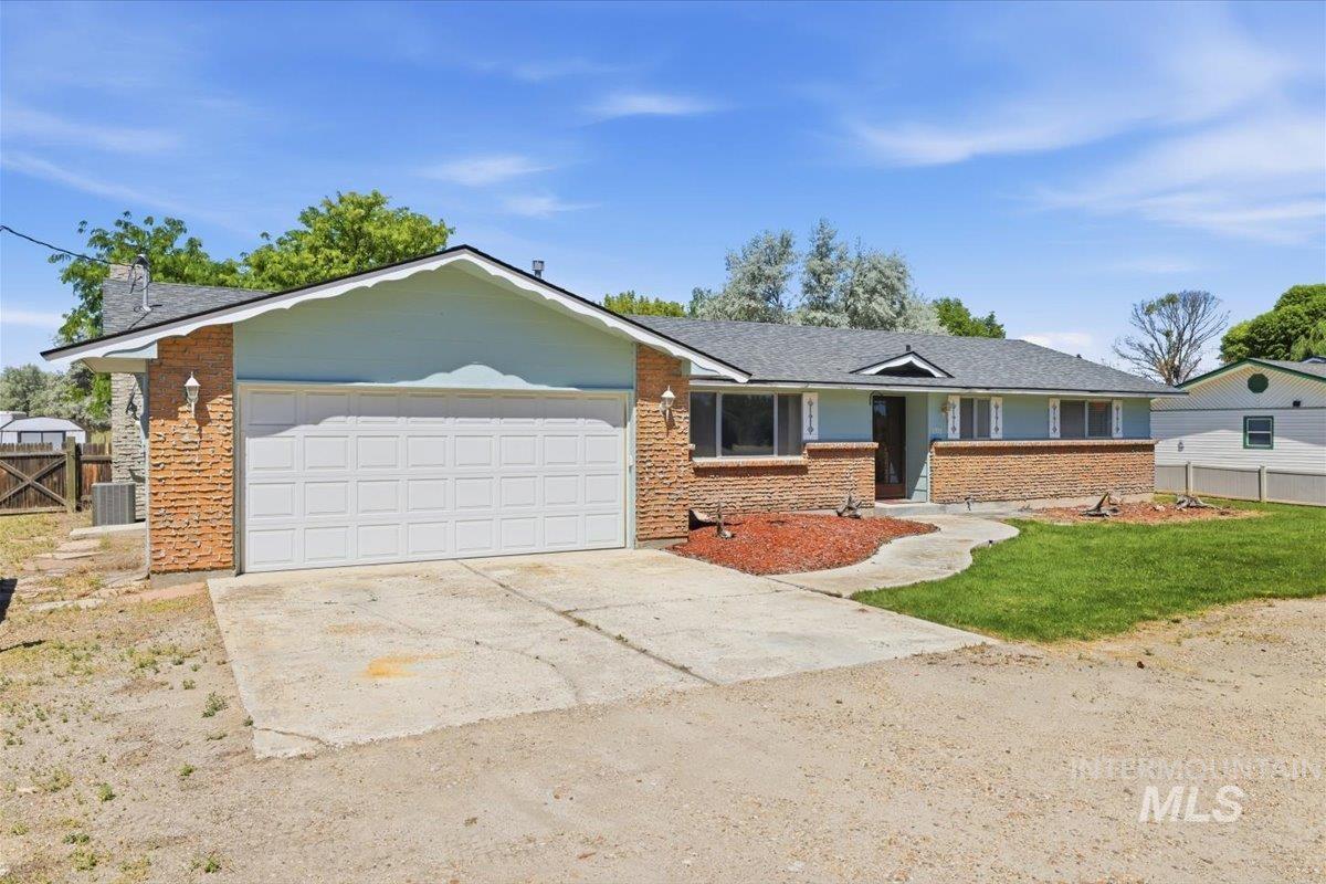 1311 North Middleton Road Nampa, ID 83651 - Photo 3 of 49 Ranch-style residence featuring a brick facade with light blue siding, a multi-pane garage door, and a dark shingle roof