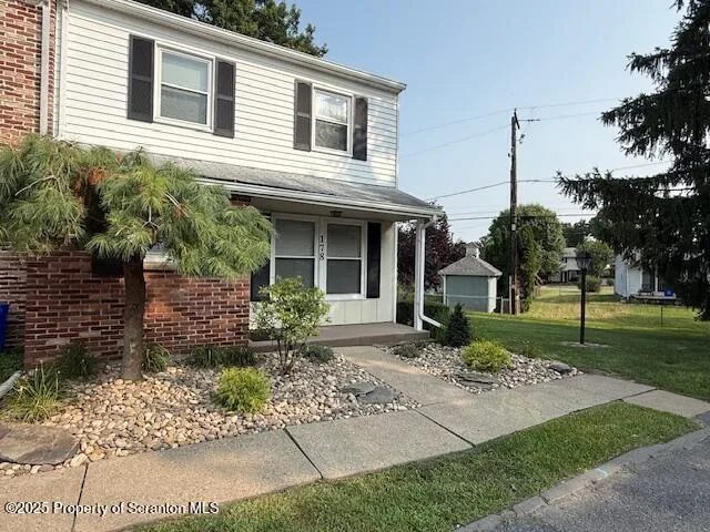 a front view of a house with garden and trees