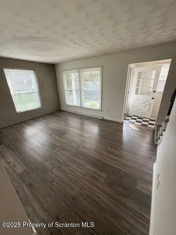 a view of an empty room with a window and wooden floor