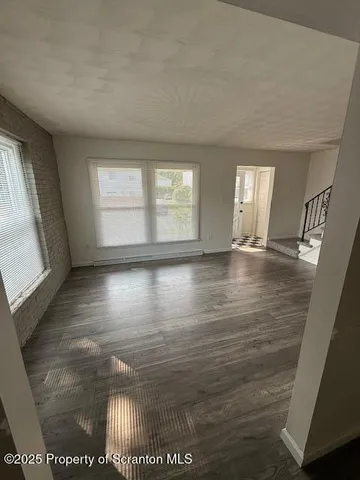 a view of an empty room with window and wooden floor