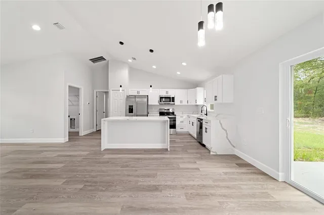 a view of kitchen with kitchen island microwave and cabinets