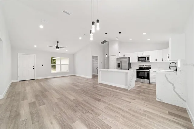a view of kitchen with kitchen island white cabinets and stainless steel appliances